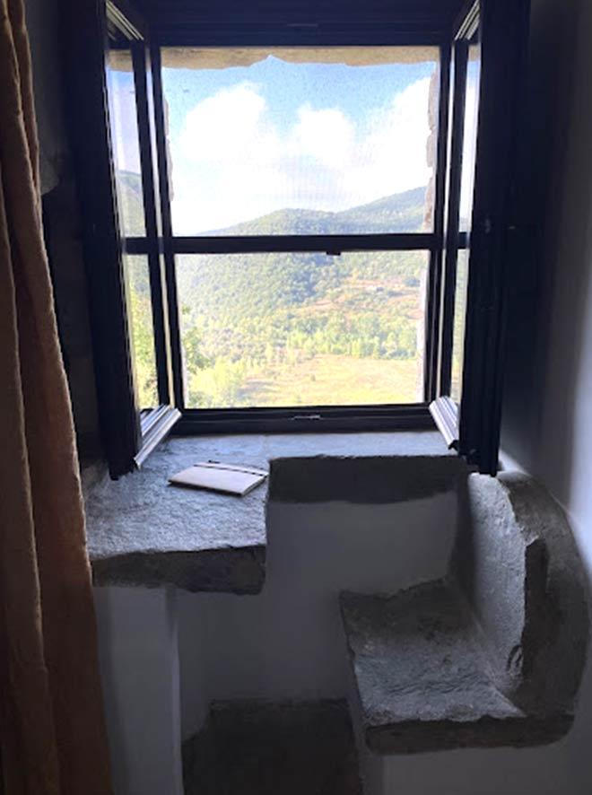 a window with a stone bench and a view of the valley